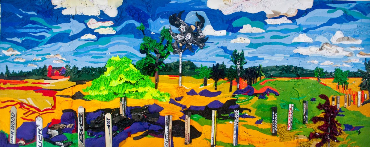 Using recycled hockey equipment, such as shoulder pads, knee pads, jerseys, and hockey sticks, the artist created a large textural collage depicting a spring landscape. There is a blue sky with various layers of dark and light blues, white clouds, a border of forest green trees in the distance as well as trees positioned throughout the landscape, fields of greens, yellows, and blues, and a surrounding fence made of broken hockey sticks.