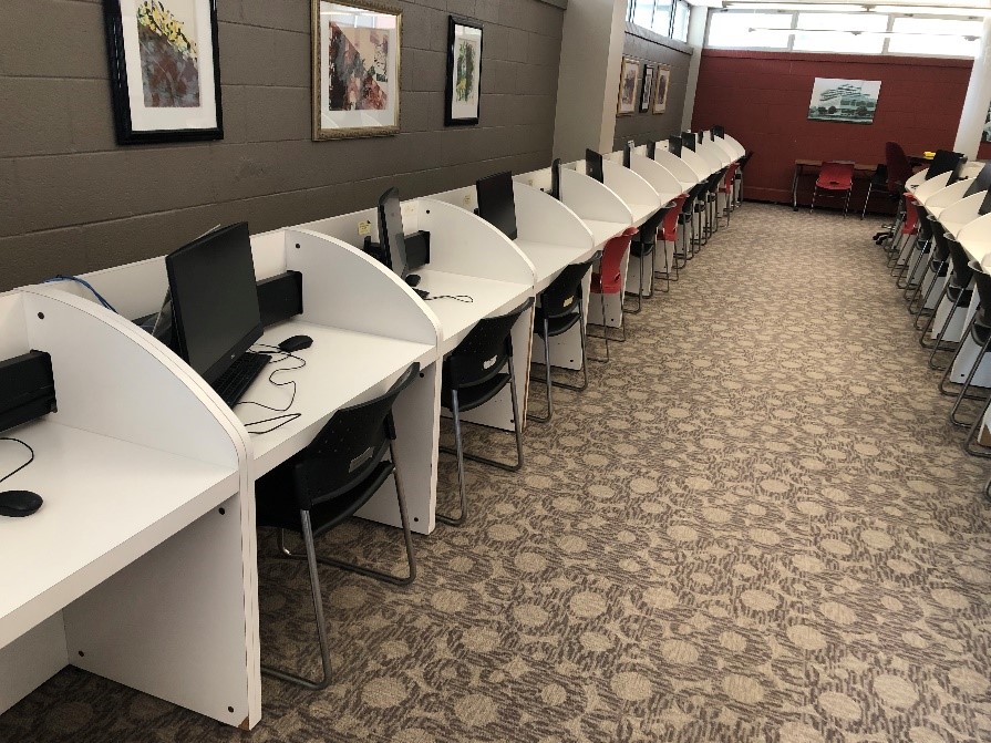 Two rows of desks with workstations in an area called the Information Commons. 