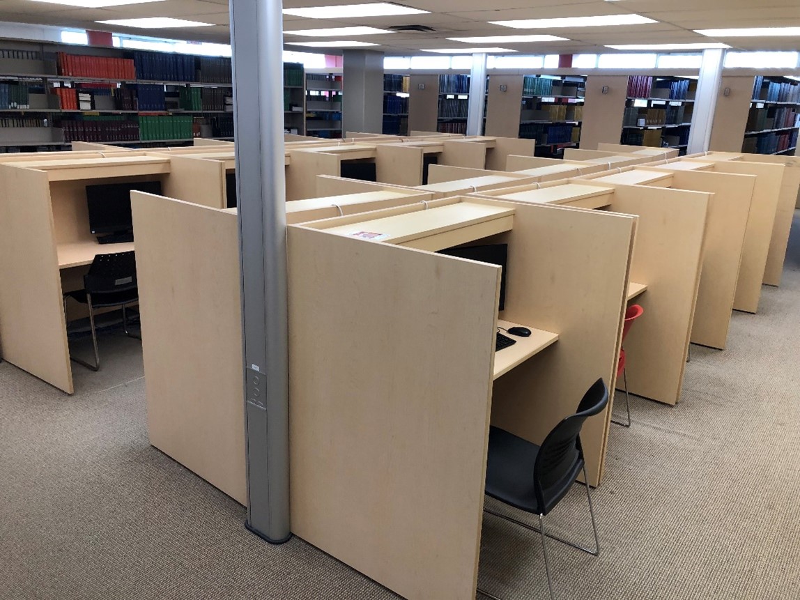 A group of about 15 study carrels with workstations in them. There are partitions between the desks for privacy.