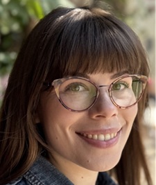 A woman with glasses smiling gently into the camera.