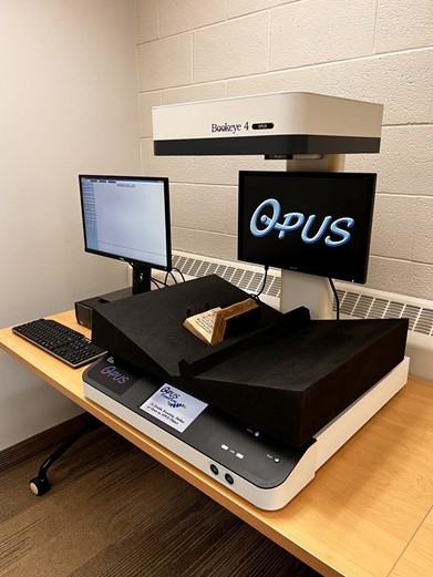 Overhead scanner attached to a computer. The Noted Hymnal is placed on a book cradle underneath the overhead scanner.