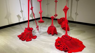 The interior exhibit. Various figures made of red netted fabric with narrow sections lifting towards the ceiling